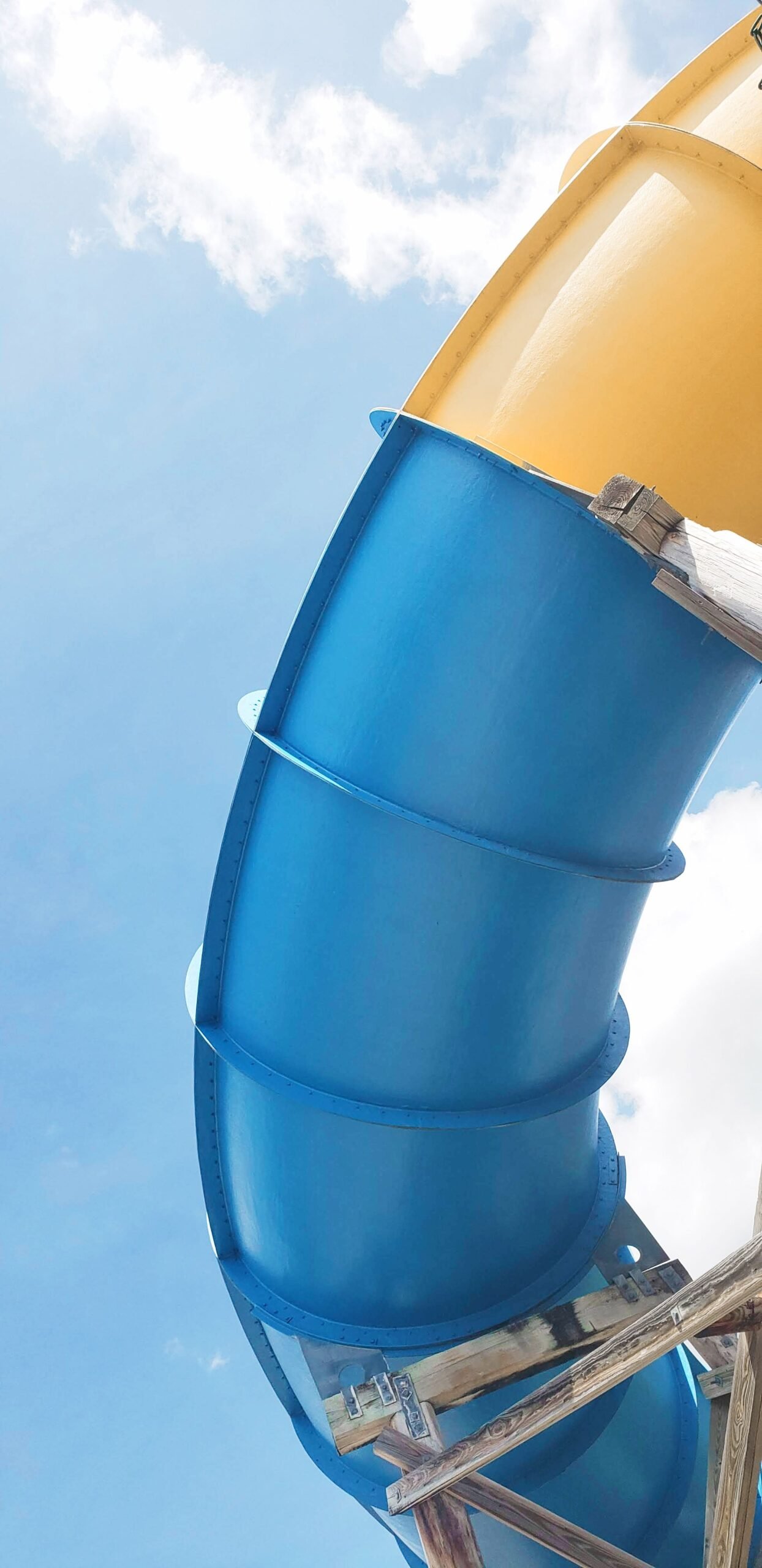 A tall blue and yellow water slide against a clear summer sky