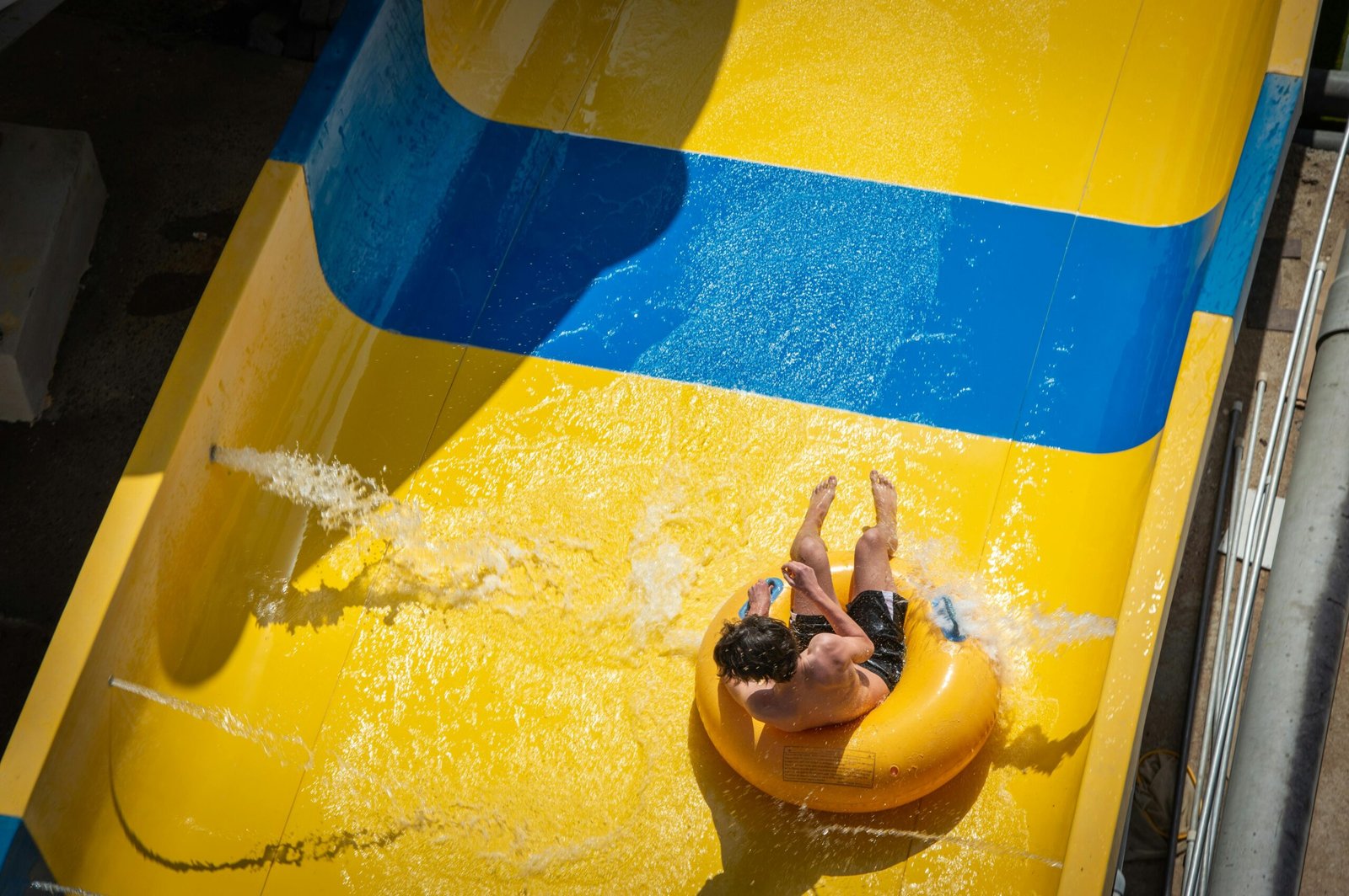 A rider speeding down a yellow water slide on an inner tube