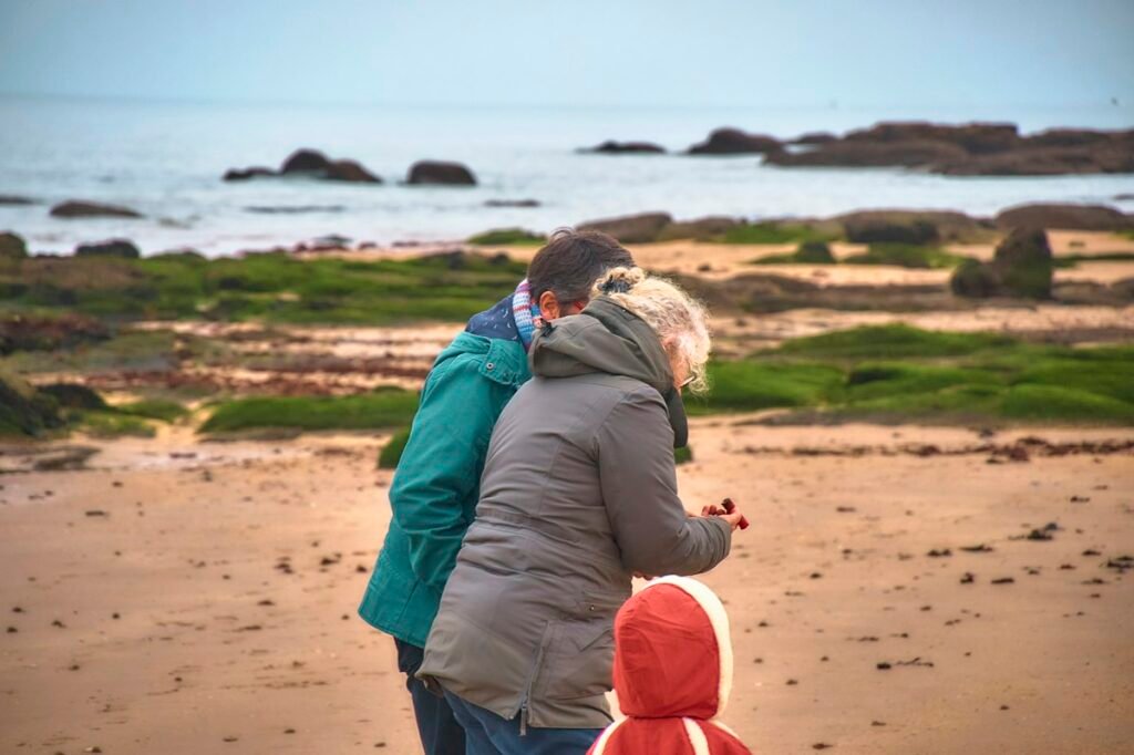 Family exploring a rocky beach with a toddler in a red raincoat